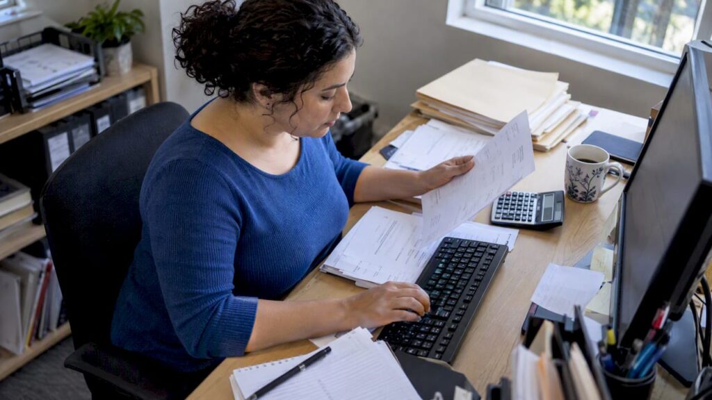 Bookkeeper reviewing invoices at her workstation